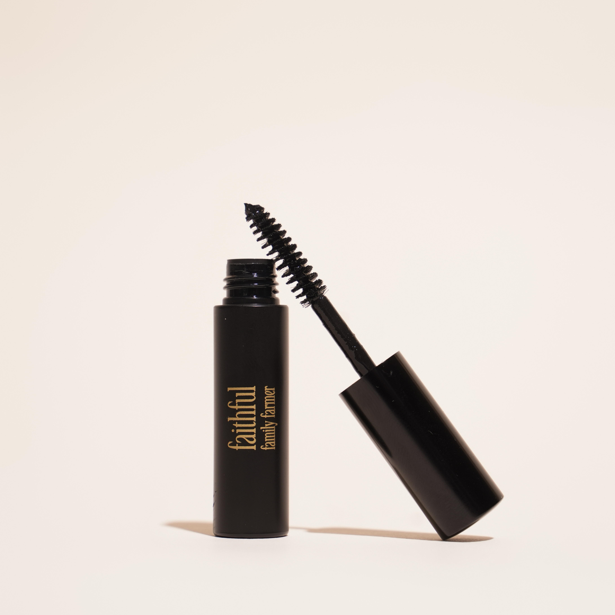 Black non-toxic mascara with open cap on a beige background