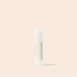 A single tube of ozonated lip balm with a white cap and a white body featuring a light sage green label, standing upright against a solid pale peach-beige background.